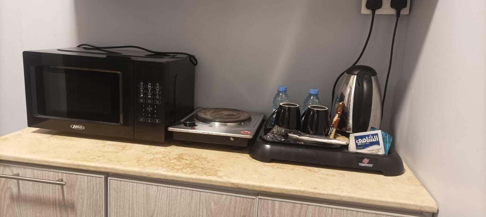 Uma cozinha com micro-ondas, chaleira e cafeteira na bancada.