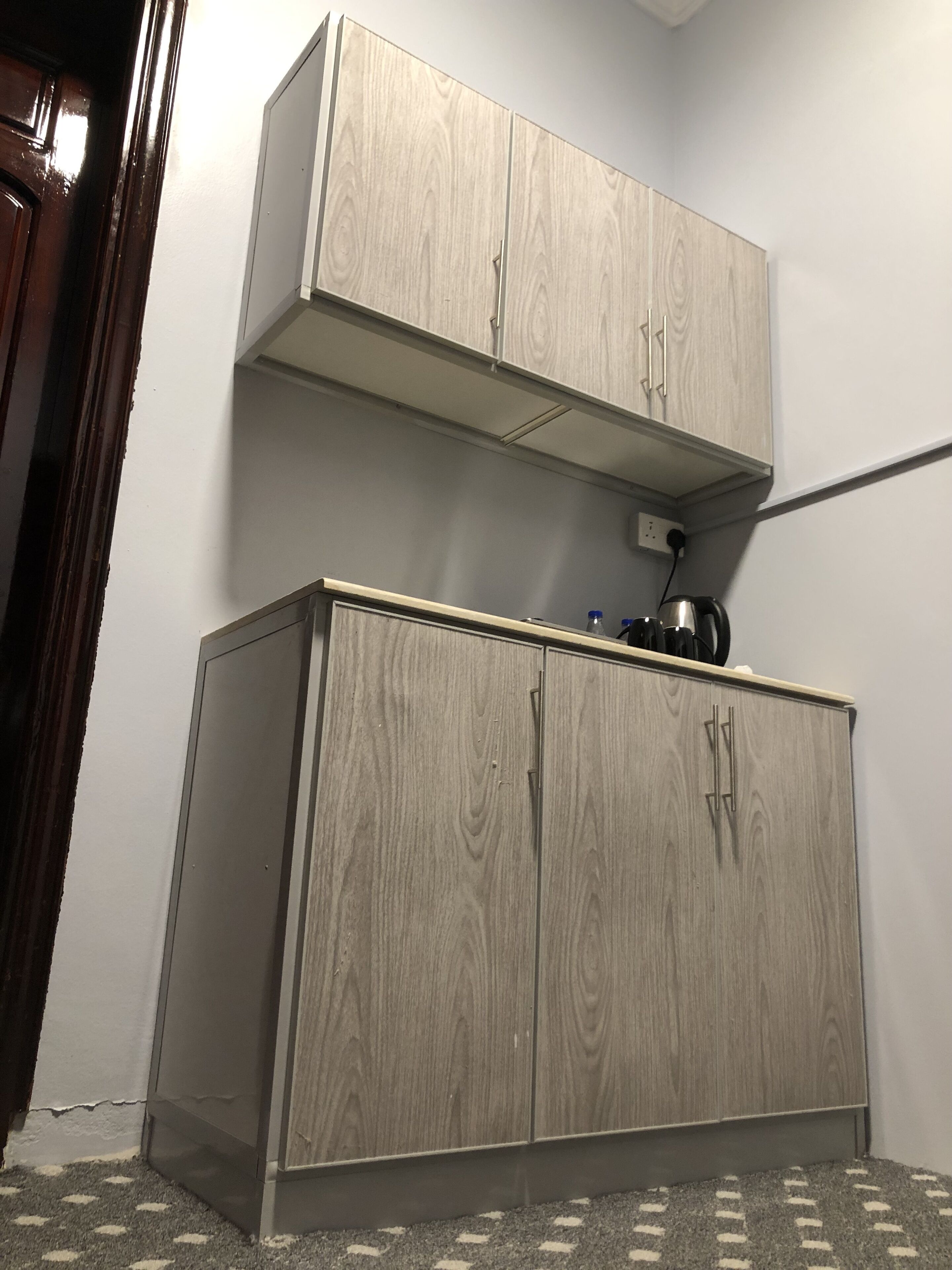 A small, compact room with a wooden wardrobe and a shelf above it.