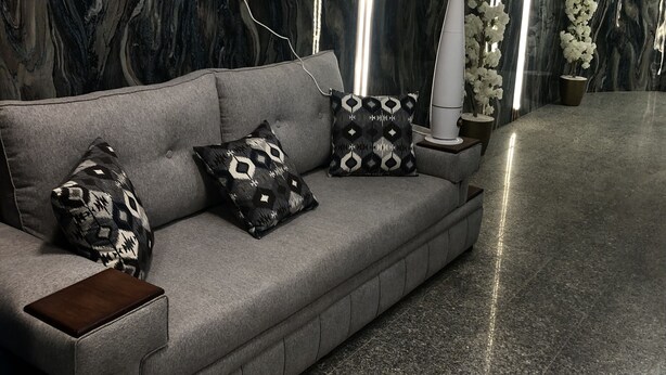 A modern living room with a grey sofa, patterned cushions, a side table, and a floor lamp. - Al Ghazali Suites (Madinah)