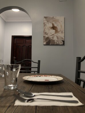A dining table with a plate, cutlery, and a glass. There is a chair and a door in the background. - Al Ghazali Suites (Madinah)