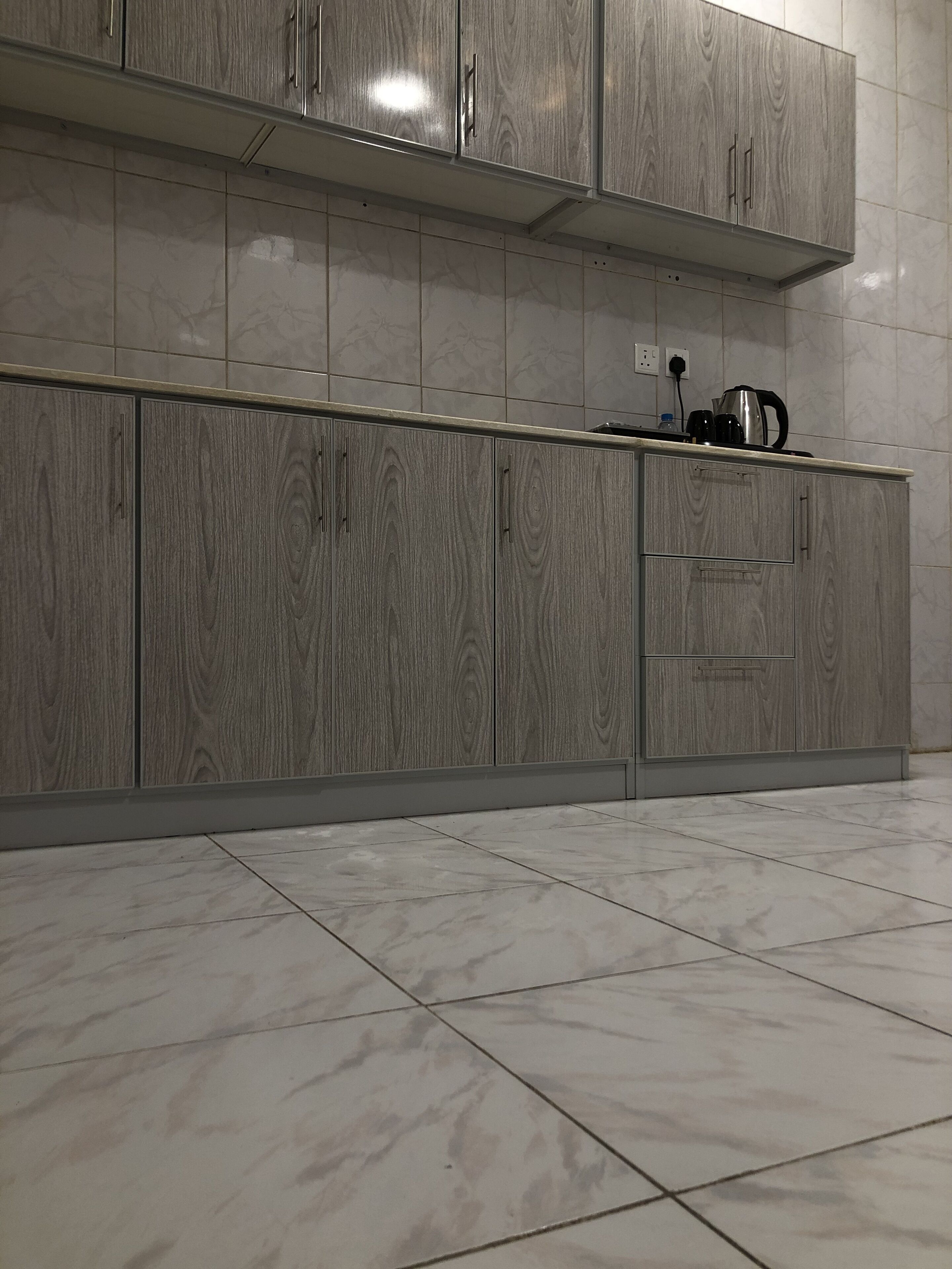 A kitchen with grey wooden cabinets, a countertop, and a tiled backsplash.
