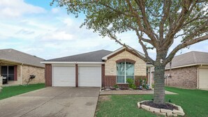 A residential house with a garage, a well-maintained lawn, and a tree in the front yard.