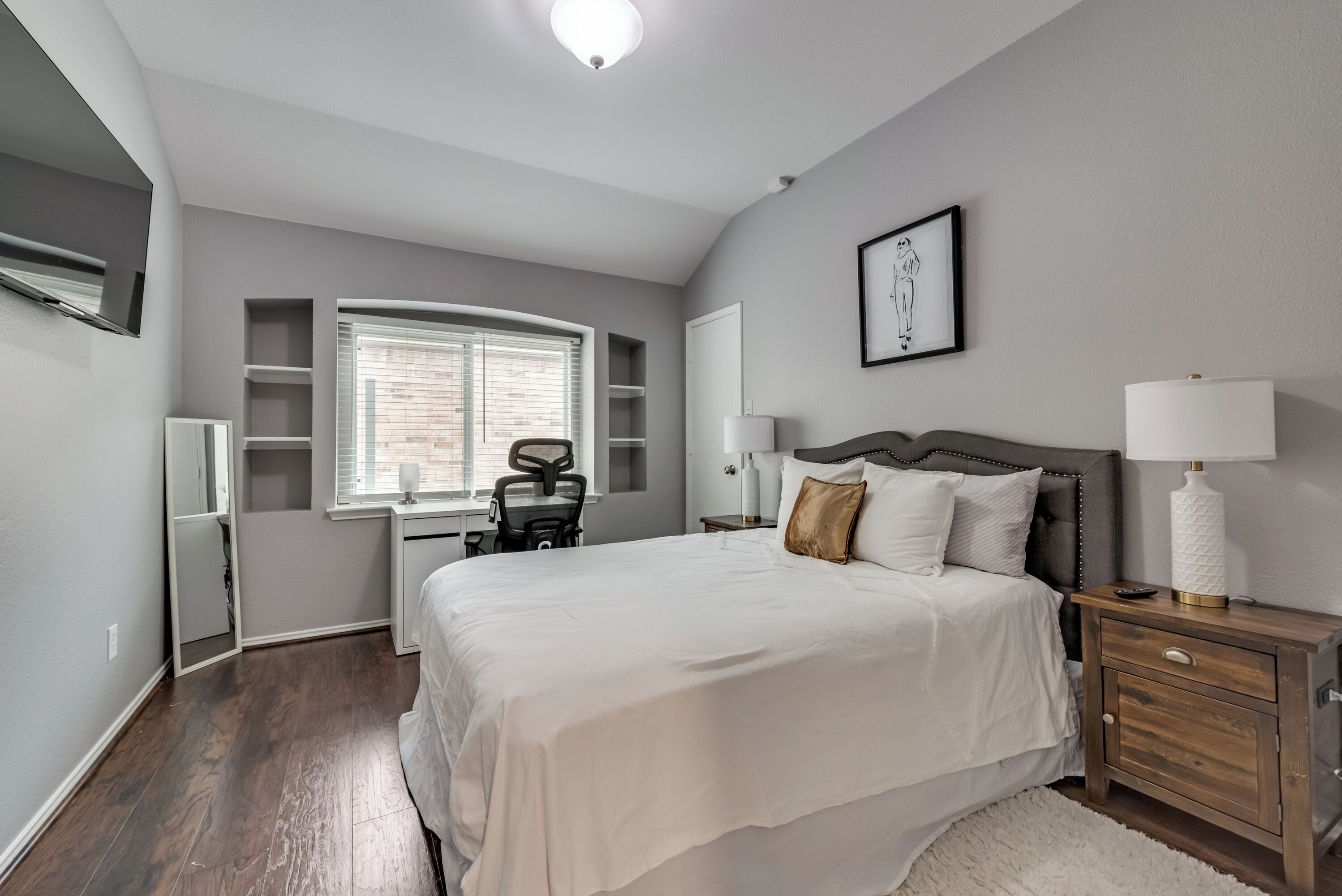 A bedroom with a bed, bedside tables, a desk, and a chair.