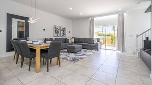 A modern living room with a dining area, grey sofas, and a large window. - Cozy, perfect for families, Hot Tub - 3013 (Kissimmee)