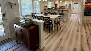 A spacious kitchen with a central island, wooden flooring, and white cabinetry. - Private Sea Pines Home w Large Deck. Great for couples! (Hilton Head Island)