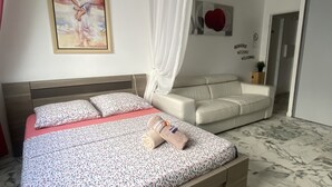 Ein Schlafzimmer mit Bett, einer Couch, einem Gemälde und einem Willkommensschild.