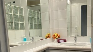 Ein Badezimmer mit weißen Fliesen, einem Waschbecken und einem Spiegel.