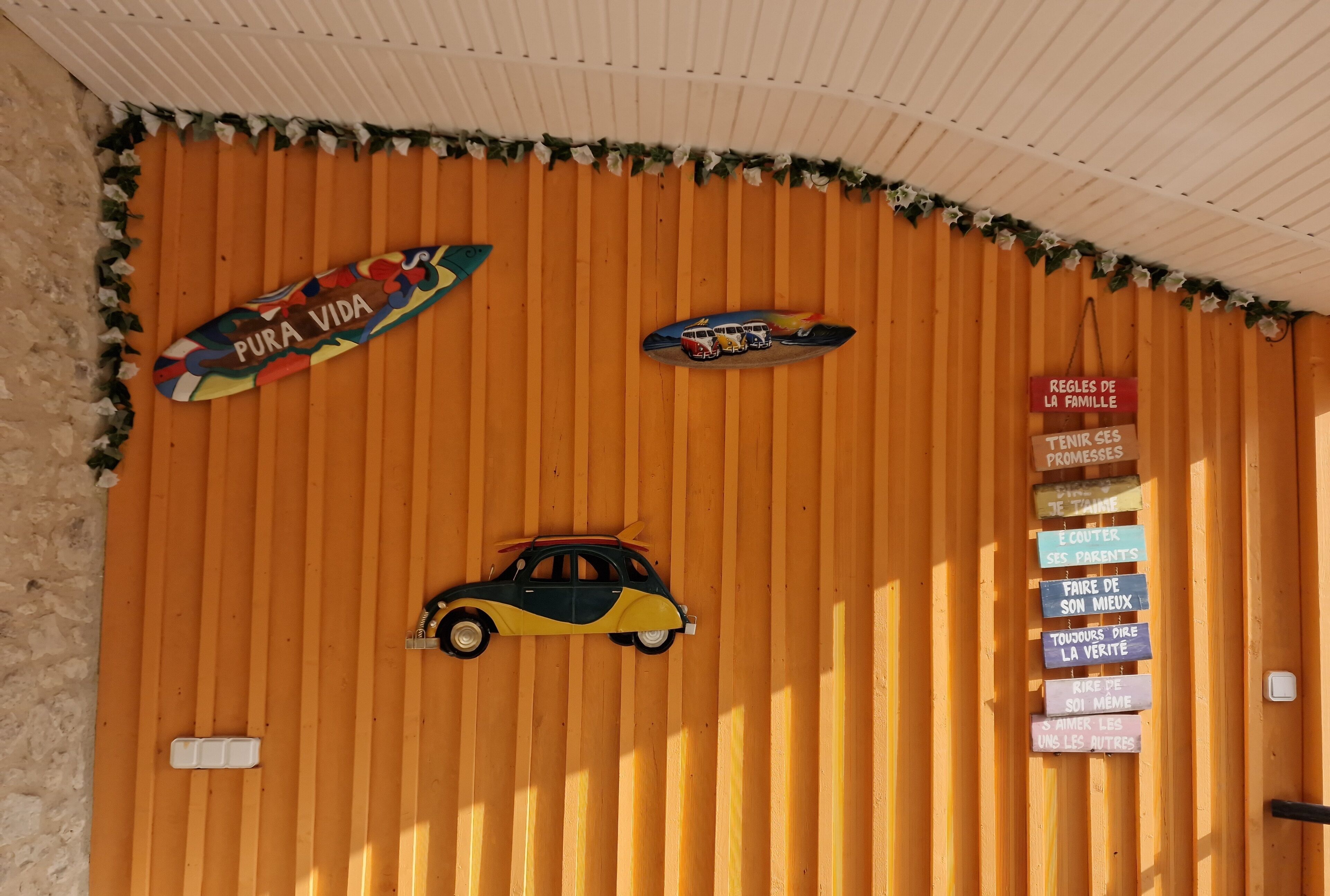 A wooden wall with a car, a surfboard, and a sign with family rules.
