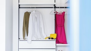 Un dormitorio con cama, un armario blanco y una percha para ropa.