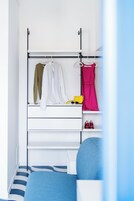Un dormitorio con cama, un armario blanco y una percha para ropa.