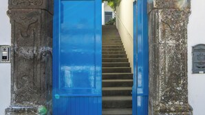 Un arco de piedra con una puerta azul que da a una escalera.