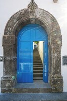 Un arco de piedra con una puerta azul que da a una escalera.