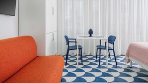 Una habitación con una cama, un sofá, una mesa con sillas y un televisor fijado en la pared.