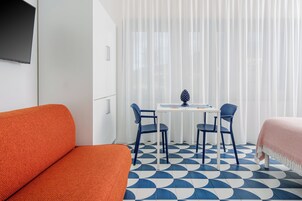 Una habitación con una cama, un sofá, una mesa con sillas y un televisor fijado en la pared.