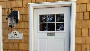 A white front door with a small window above it, a "No Smoking/Vaping" sign, and a house number sign reading "14 The Willow".