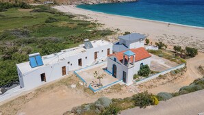 Un edificio costero con techo plano, un pequeño jardín y vista a la playa y al océano.