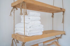 Een houten plank met touwen die een stapel witte handdoeken vasthouden.