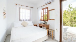 Un dormitorio con cama, un escritorio de madera, una silla y una ventana con cortinas.
