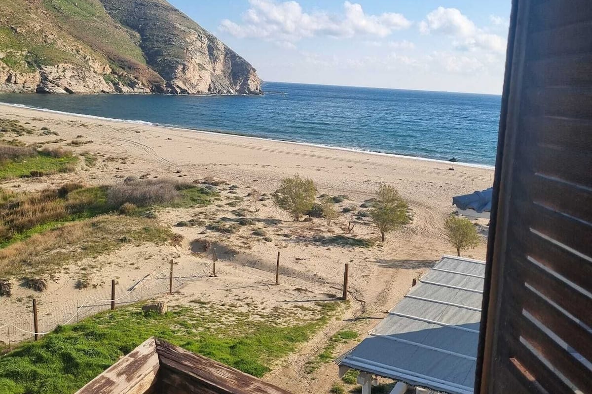 Ein Strand mit Blick auf den Ozean und eine gebirgige Landschaft.