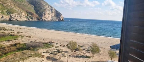 A beach with a view of the ocean and a mountainous landscape.