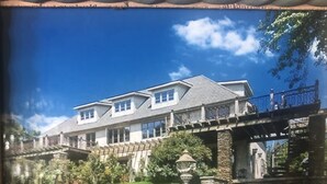 A large, two-story house with a stone bridge leading to a balcony.