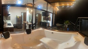Un interior moderno con una bañera grande, techo de madera y vistas al área del balcón exterior.