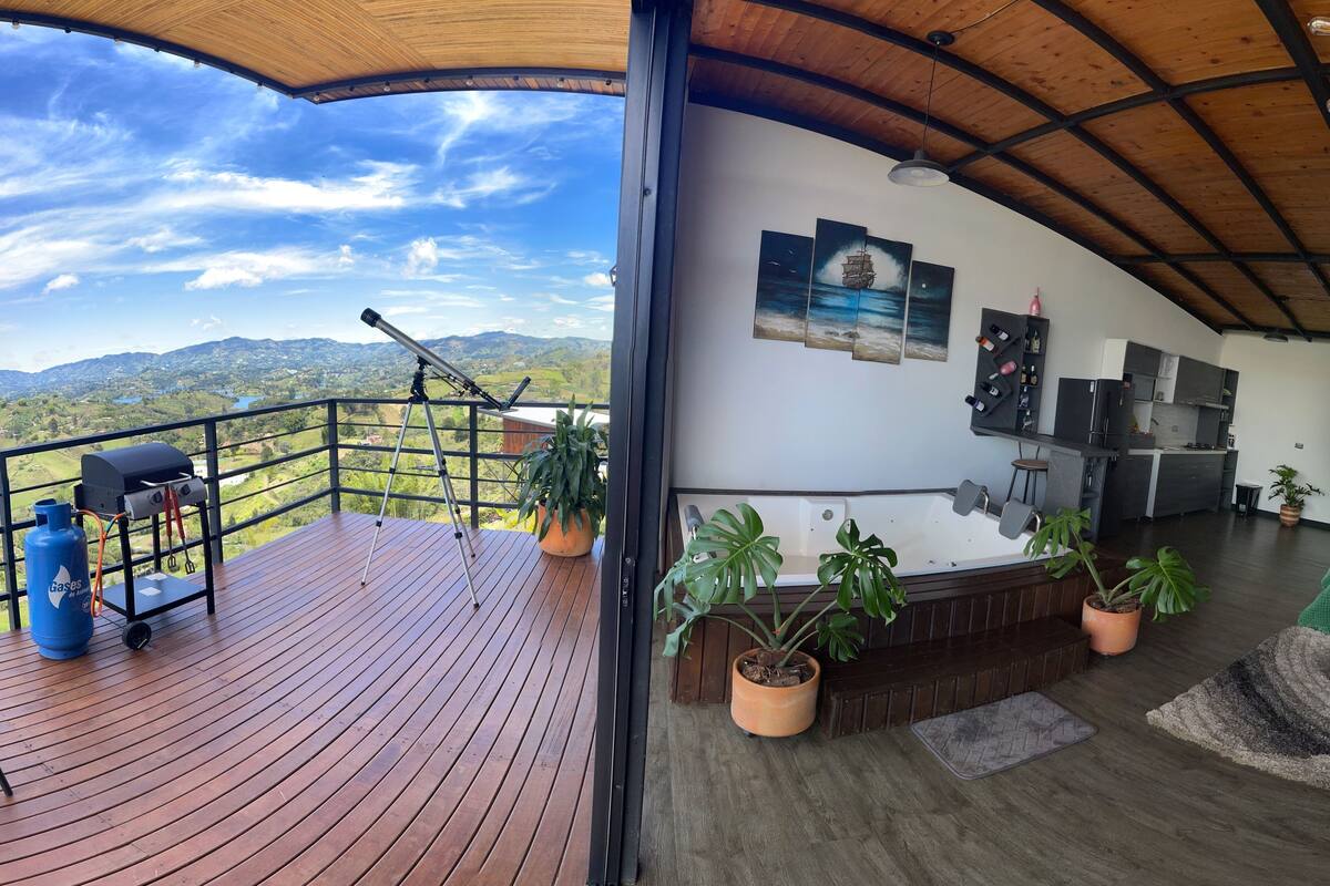A spacious deck with a view of mountains, a barbecue setup, and a hot tub.
