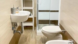 A bathroom with a toilet, bidet, and a shower enclosure. - Big fish Affittacamere (Alghero)