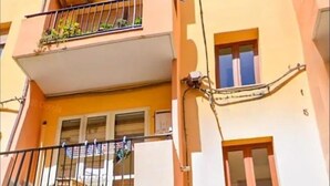 A multi-story building with balconies, a stone facade, and a door with a sign. - Big fish Affittacamere (Alghero)