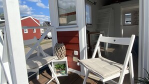 A wooden deck with two white folding chairs and a small table with plants. - Tiny Haus am Meer (Heringsdorf)