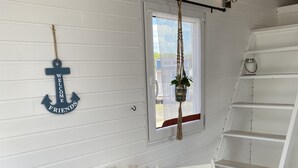 A cozy room with a round wooden table, white chairs, a hanging plant, and a ladder. - Tiny Haus am Meer (Heringsdorf)