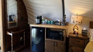 Una cocina compacta equipada con refrigerador, microondas, cafetera y un pequeño armario.