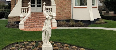 Ein prachtvolles Gebäude mit einem markanten Eingang, einem Balkon und einer Statue im Garten.