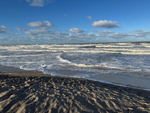 Ein Strand mit Wellen und blauem Himmel.