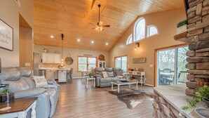A spacious living room with a leather sofa, a stone accent wall, and a dining area with a wooden table. - Secluded 5 BR Modern Cabin, 120 acres. New River Trail, Claytor Lake, VA tech (Draper)