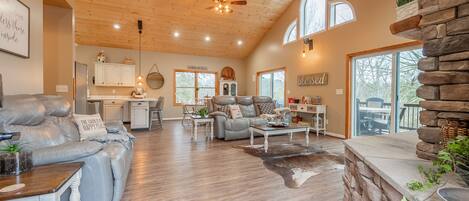 A spacious living room with a leather sofa, a stone accent wall, and a dining area with a wooden table.