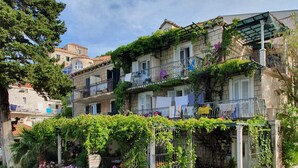 Un edificio de piedra tradicional con un porche cubierto, plantas en macetas y un cartel que indica un restaurante.