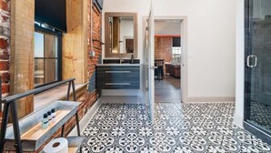 A modern kitchen with a brick wall, a wooden bench, and a patterned floor.