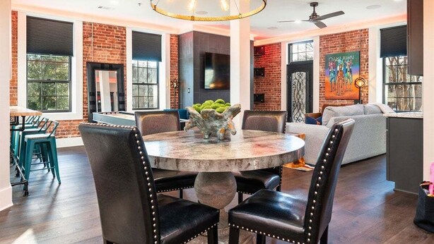 A dining area with a round table, chairs, and a chandelier.