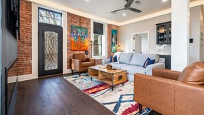 A modern living room with a brick wall, a sofa, a coffee table, and a TV.