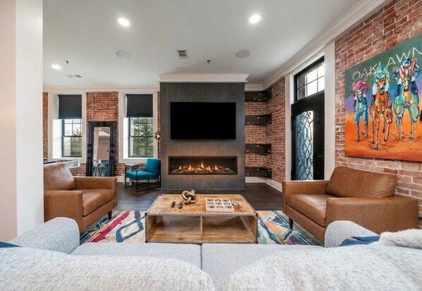 A living room with a fireplace, leather sofas, a coffee table, and a large TV.