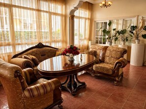 A spacious room with a large round table, two sofas, and a potted plant. - Brand otel (Didim)