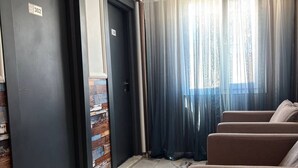 A hotel room with a marble floor, a seating area with sofas, and a large window with sheer curtains. - Brand otel (Didim)