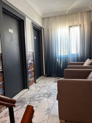 A hotel room with a marble floor, a seating area with sofas, and a large window with sheer curtains. - Brand otel (Didim)