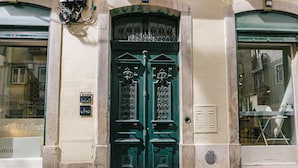 A green double door with intricate metalwork, a small sign above the door, and a window to the right. - RENT4REST CASTLE VIEW FAMILY & FRIENDS BAIRRO ALTO (Lisboa ciudad)