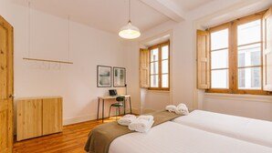 A hotel room with two beds, wooden flooring, a desk with a chair, a small table, and a hanging light fixture. - RENT4REST CASTLE VIEW FAMILY & FRIENDS BAIRRO ALTO (Lisboa ciudad)