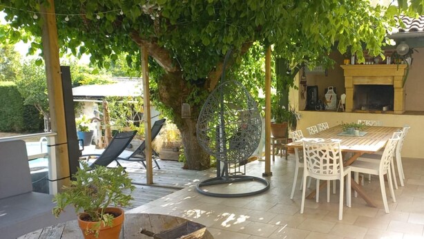 A patio with a table and chairs, a hanging chair, and a barbecue area. - Character house with swimming pool (Bergerac)