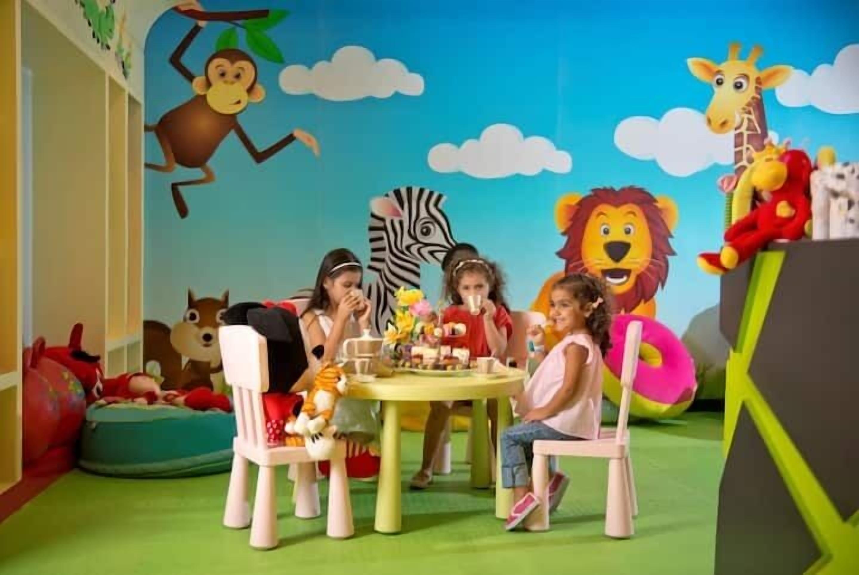 Une salle de jeux pour enfants avec une table ronde, des chaises et divers jouets en peluche.