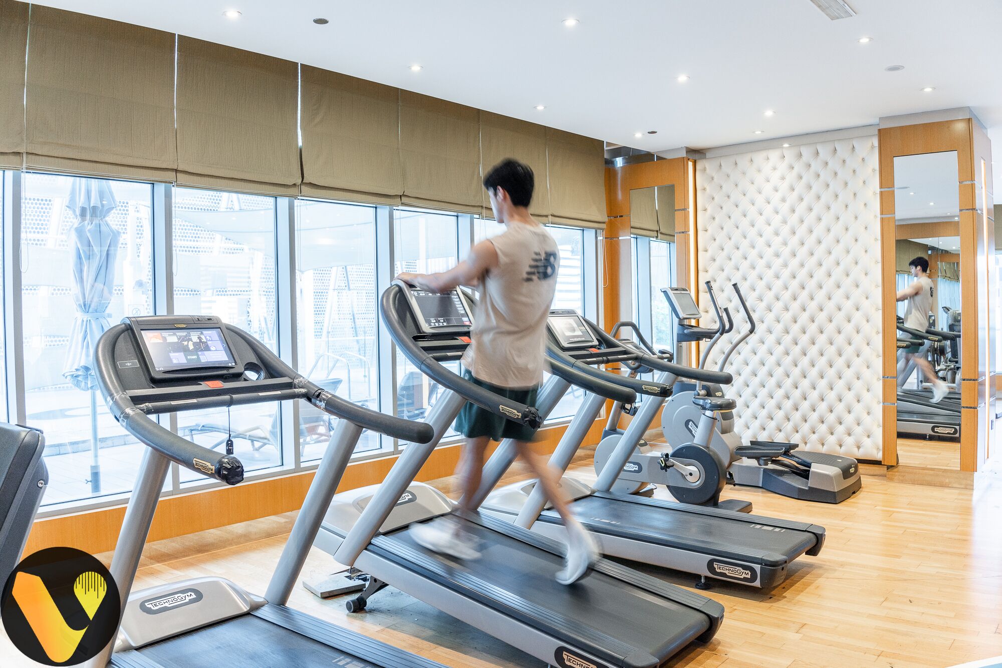 Ein Fitnessraum mit Laufbändern, Ergometer und einer Spiegelwand.