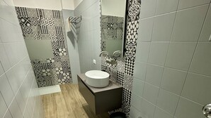 Een badkamer met een houten vloer, een wastafel, een toilet met bidetfunctie en een toilet.